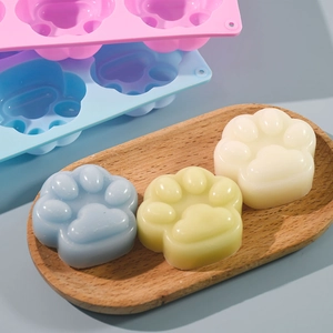 Detail view of cat paw silicone mold with finished pastel resin crafts on wooden tray