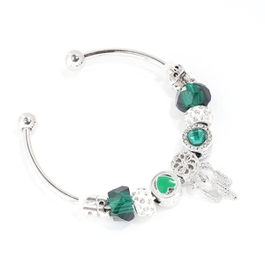 Detail of silver bangle with dark green beads and heart feather charms on white background
