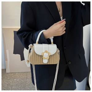 Détail du sac élégant en paille tressée avec fermoir fleur dorée et rabat en cuir blanc