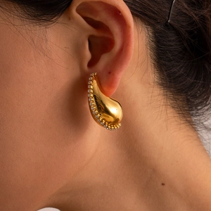 Close-up of 18K gold teardrop earring with cubic zirconia on female model