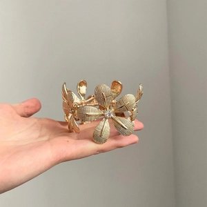 Close-up of golden floral bracelet featuring textured petals and sparkling crystals