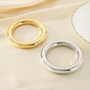 Nahaufnahme von polierten Gold- und Silberarmreifen auf elegantem Seidenstoff