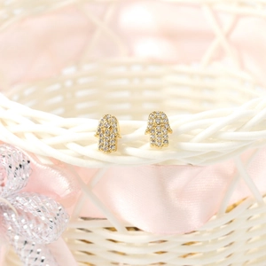 Detail of Hamsa hand earrings with white cubic zirconia set in gold plating on a basket
