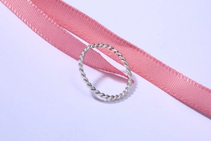 Detailaufnahme eines minimalistischen Silberrings mit Kordelmuster und Glanz