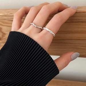 Close-up of S925 sterling silver woven and wavy rings on a hand with natural light
