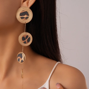 Golden earrings with tiered round leopard print panels worn by a model in profile