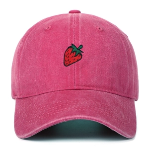 Close-up of red strawberry embroidery on a vintage washed rose red cotton baseball cap