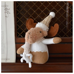 Detailed close-up of plush Christmas reindeer toy with sequined hat on wooden background