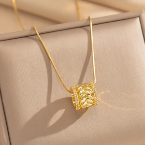 Detailed view of gold wheat ear cylinder pendant with sparkling stone edges on a chain