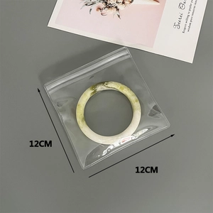 Macro detail showing 12x12cm transparent PVC jewelry pouch containing a jade bangle
