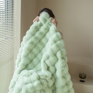 Close-up of soft mint green faux rabbit fur blanket with luxury wavy plush texture