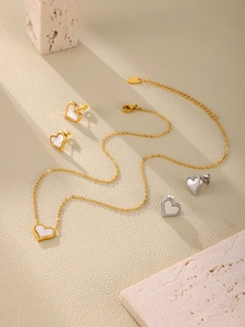 Detail view of heart-shaped jewelry set with mother of pearl inlay on textured stone background