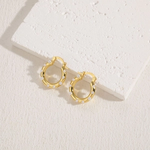 Gros plan de boucles d'oreilles anneaux dorés avec perles sur pierre blanche