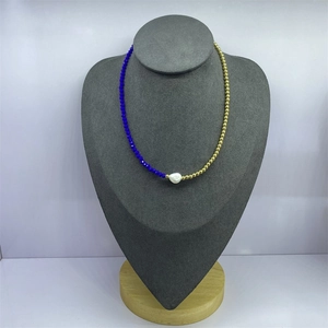 Detail of baroque pearl necklace with blue glass beads and gold metal spheres on a bust