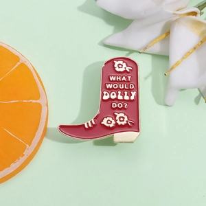 Red cowboy boot enamel pin with What Would Dolly Do text on a fresh green background