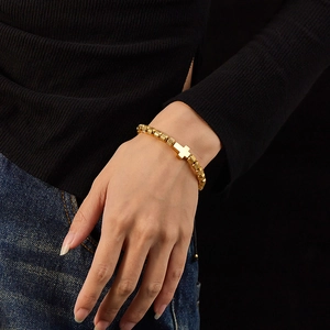 Detail of adjustable gold stainless steel bead bracelet with a cross charm on wrist