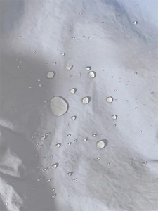 Detailed view of the water-repellent fabric showing water beads on the tote bag surface