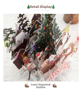 Close-up of 3D laser-cut Christmas card showing detailed layers of snowy cabins and reindeer