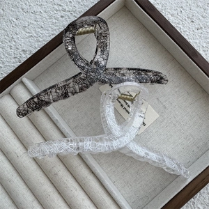 Macro detail of large hair claw clips featuring lace mesh texture and resin finish