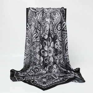 Détail d'un foulard en soie à motif paisley noir et blanc drapé sur un présentoir