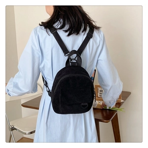 Rear view of a model wearing the mini black corduroy backpack with vertical texture
