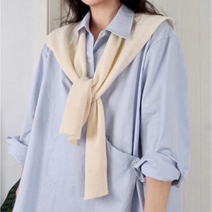 Light blue cotton shirt layered with a soft cream knit shawl over the shoulders