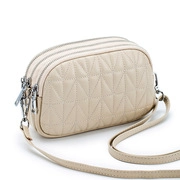 Detailed view of beige leather clutch bag with geometric quilting and three silver zippers