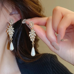 Detailed view of elegant gold leaf earrings with pear-shaped pearls and marquise crystals