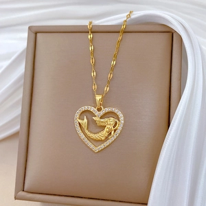 Elegant gold heart necklace with mermaid relief and crystals on beige jewelry box display