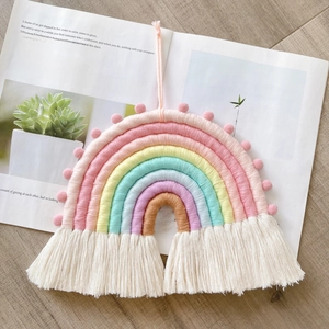 Detail of handmade macrame rainbow wall hanging with soft cotton tassels on wooden desk