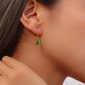 Detail of a teardrop green stone earring with a gold hoop shown on a female ear