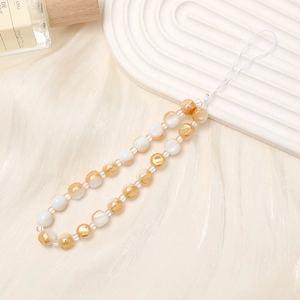 Beaded pearl and amber crystal phone charm strap on champagne silk background