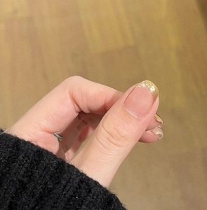 Detail of French manicured press-on nails with golden glitter tips and bow accents