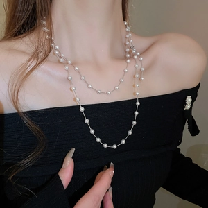 Gros plan d'un collier double épaisseur à perles fantaisie sur un pull noir