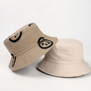 Close-up of reversible cotton bucket hat showing khaki smiley print and white fabric