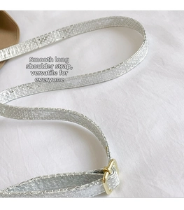 Détail macro d'une bandoulière argentée texture serpent avec boucle en métal doré