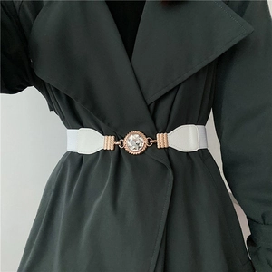 White elastic waist belt with gold rhinestone buckle worn over a green trench coat