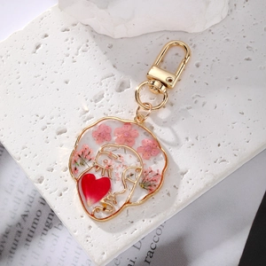 Macro detail of epoxy resin keychain with gold wire face outline and dried pink flowers