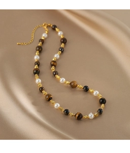 Détail macro de pierres œil de tigre et de perles sur un collier avec fermoir doré