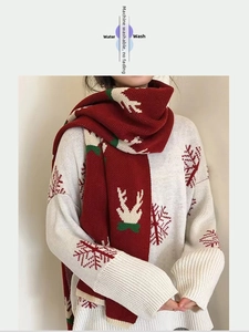 Detail of red Christmas scarf with reindeer pattern and white knitted sweater
