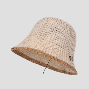 Close-up of beige breathable crochet knit bucket hat with brown trim and metal bow charm