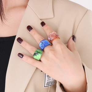 Detailed view of three stackable wide rings in green, blue, and pink on model's hand
