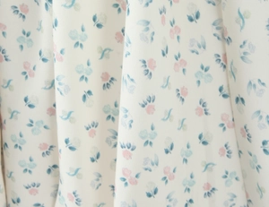 Détail de tissu floral avec motifs de roses roses et bleues sur textile blanc