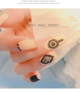 Detailed view of luxury gold nail caviar beads and black rhinestone accessories in a grid box