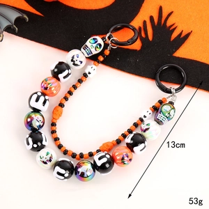 Halloween beaded phone strap with pumpkin and skull charms on a festive background
