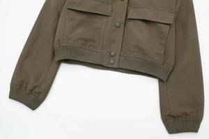 Detail of cargo jacket showing flap pockets, button closure, and ribbed elastic hemline