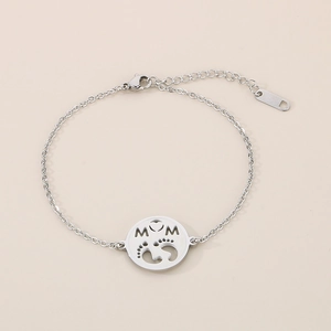Close-up of silver steel bracelet featuring a round MOM pendant with baby footprints