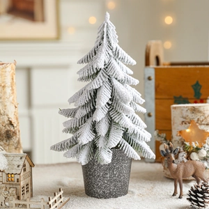 Miniature flocked Christmas tree with snow effect in a frosted pot for festive tabletop decor