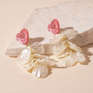 Détail des boucles d'oreilles cœur en résine rose avec pétales de fleurs nacrés