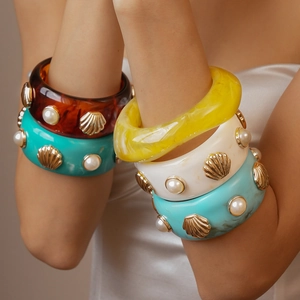 Detail of bohemian resin bangles with gold seashells and faux pearls for a summer look